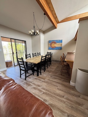 A dining area with a wooden table and chairs, a chandelier, and a painting on the wall.
