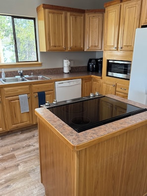A kitchen with wooden cabinets, a dishwasher, a stove, and a microwave. - Beautiful 3 Bedroom/2.5 bath Condo Steps from Downtown Winter Park (Winter Park)
