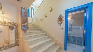 A staircase leading to a room with a blue door, a decorative mirror, and wall-mounted lights. - Spacious villa with private pool (Red Sea Governorate)