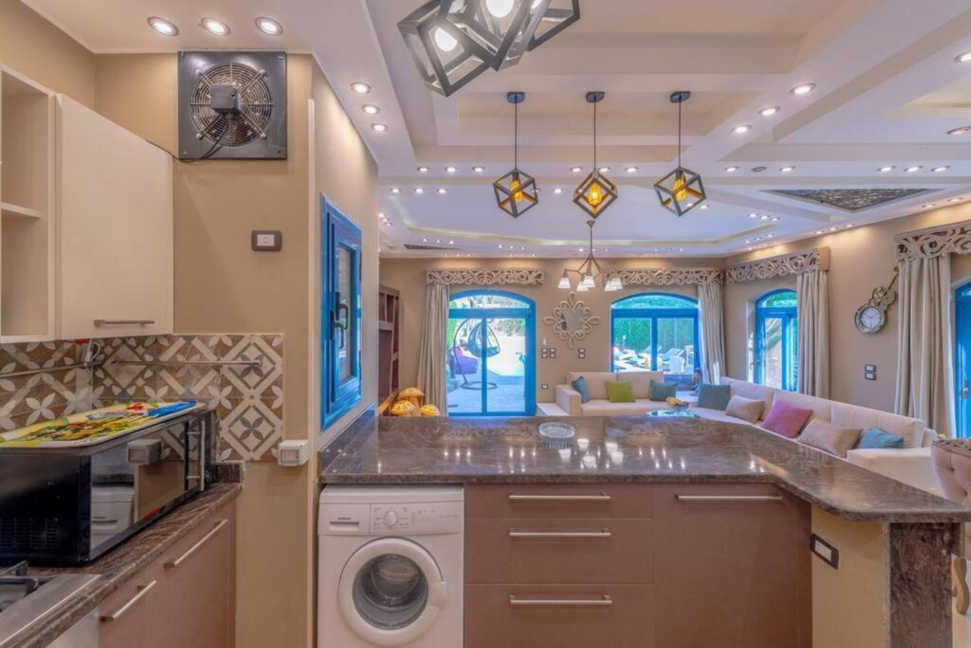 Una cocina moderna con lavadora incorporada, un comedor con sofá y vistas al exterior.