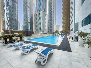 A rooftop pool with lounge chairs, surrounded by high-rise buildings. - Free Housekeeping Visits During Your Stay - Stayshort - Bright 1 Bedroom Retreat in Dubai Marina That Sleeps 2 (Dubai)