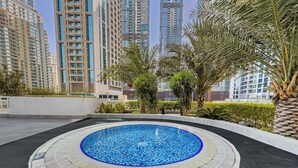 A rooftop swimming pool with a tiled edge, surrounded by a low wall and palm trees. - Free Housekeeping Visits During Your Stay - Stayshort - Bright 1 Bedroom Retreat in Dubai Marina That Sleeps 2 (Dubai)