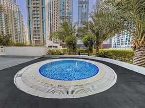 A rooftop swimming pool with a tiled edge, surrounded by a low wall and palm trees. - Free Housekeeping Visits During Your Stay - Stayshort - Bright 1 Bedroom Retreat in Dubai Marina That Sleeps 2 (Dubai)