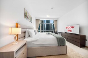 A modern hotel room with a bed, bedside table, lamp, TV, and a view of the cityscape. - Free Housekeeping Visits During Your Stay - Stayshort - Bright 1 Bedroom Retreat in Dubai Marina That Sleeps 2 (Dubai)