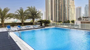 A rooftop swimming pool with lounge chairs and palm trees, surrounded by high-rise buildings. - Free Housekeeping Visits During Your Stay - Stayshort - Bright 1 Bedroom Retreat in Dubai Marina That Sleeps 2 (Dubai)