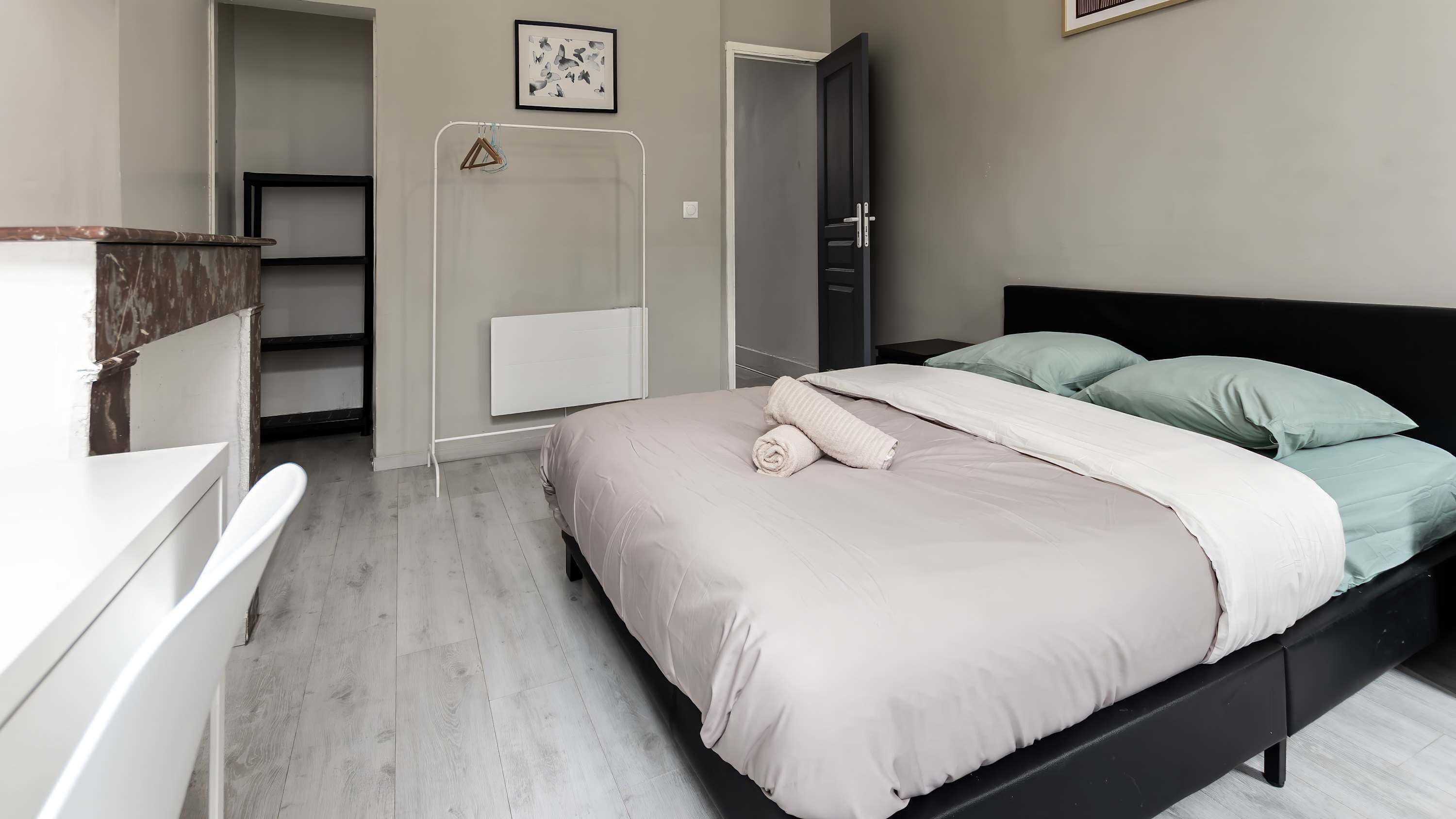 A bedroom with a bed, a bedside table, a wardrobe, and a door.