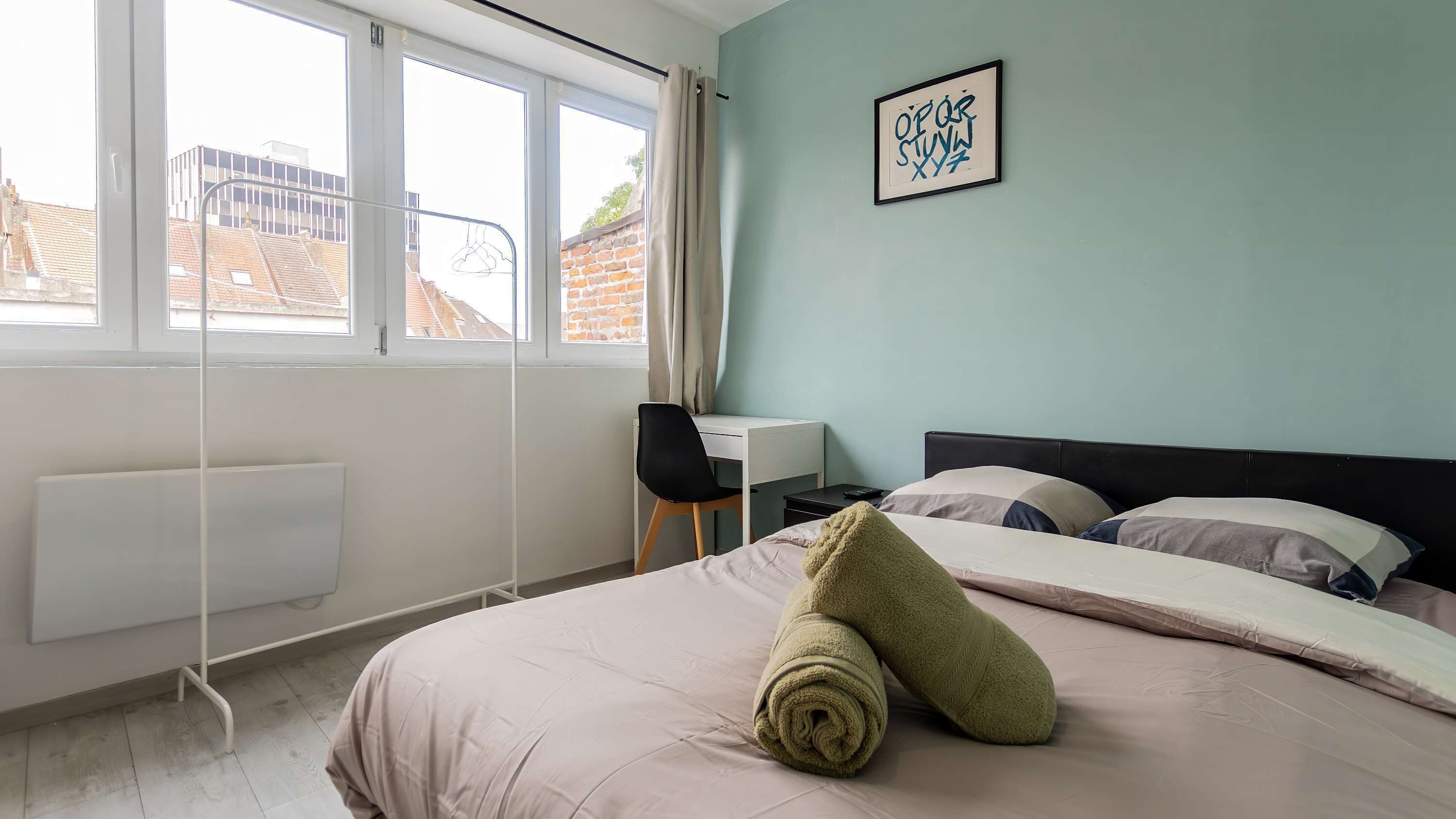 Une chambre à coucher avec un lit, un bureau et une fenêtre.