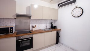 A modern kitchen with a microwave, oven, sink, and a clock on the wall. - En d Placement a Douai Location pro (Douai)