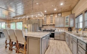 A spacious kitchen with granite countertops, stainless steel appliances, and wooden cabinetry. - Luxury 12BR Smoky Mtn. Cabin/ Sleeps 34/ Indoor Pool/ Hot tub/ Theater (Pigeon Forge)