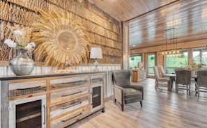 A spacious room with a wooden ceiling, a large mirror, and a dining area with chairs and a table. - Luxury 12BR Smoky Mtn. Cabin/ Sleeps 34/ Indoor Pool/ Hot tub/ Theater (Pigeon Forge)