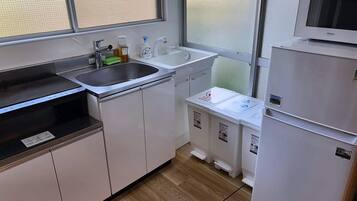 A compact kitchen with a sink, stove, microwave, and storage cabinets.