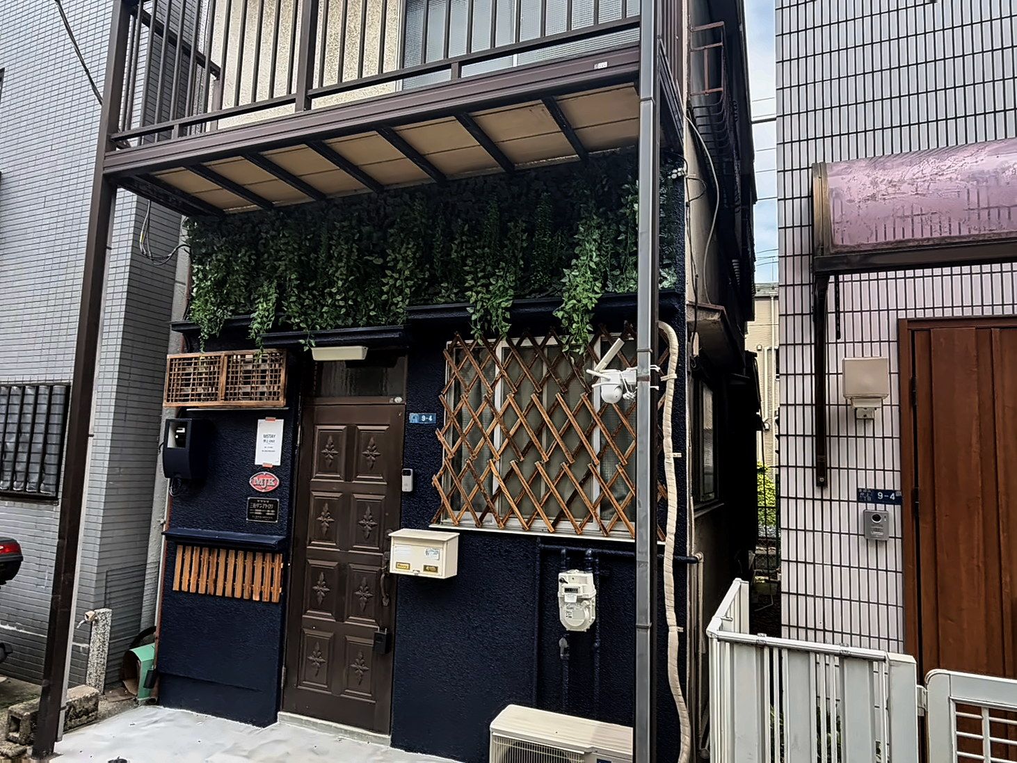 A residential building with a dark blue exterior, a brown door, and a wooden lattice fence.