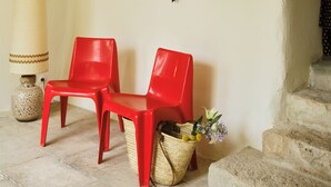 A room with two red chairs, a wall-mounted hat collection, a framed picture, a lamp, and a wicker basket with flowers. - Luxury 6BR House in Eygalières Provence - Hotel Services, Pool, Sauna (Eygalières)
