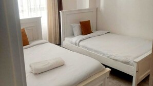 A room with two single beds, a window with curtains, and a light fixture. - The Enkang View Palace Apartment (Nairobi)