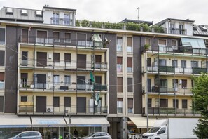 A multi-story residential building with balconies, a visible storefront, and parked vehicles. - NOVARA, 62 – Sky Loft Milan (Milano)
