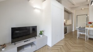 A modern living room with a flat-screen TV, a small plant, and a white entertainment unit. - NOVARA, 62 – Sky Loft Milan (Milano)