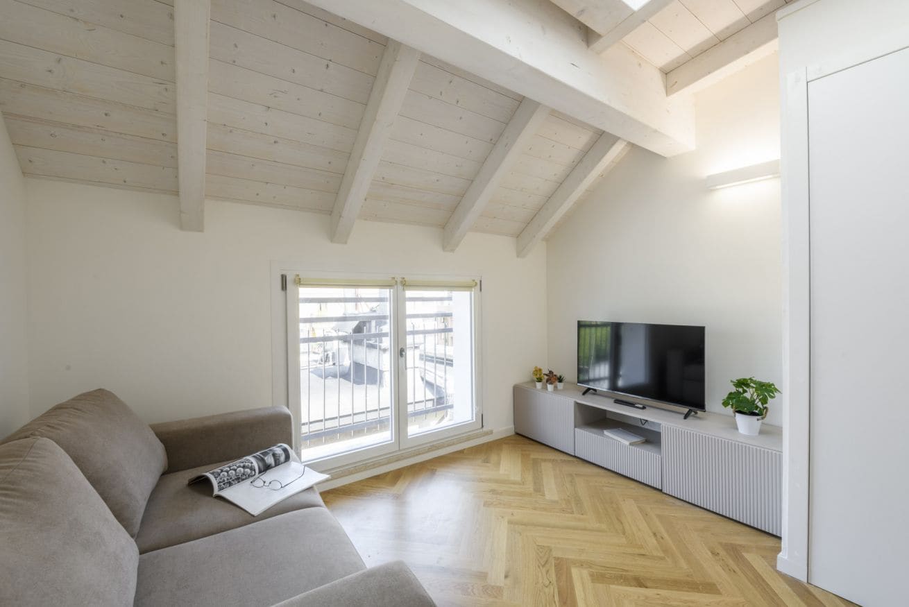 Ein modernes Wohnzimmer mit einer Couch, einem Fernseher und einem großen Fenster.