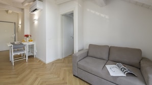 A modern living room with a sofa, a dining table with chairs, and a kitchen area. - NOVARA, 62 – Sky Loft Milan (Milano)