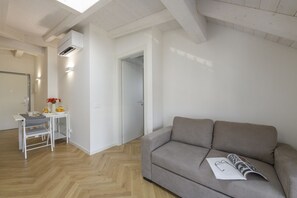 A modern living room with a sofa, a dining table with chairs, and a kitchen area. - NOVARA, 62 – Sky Loft Milan (Milano)