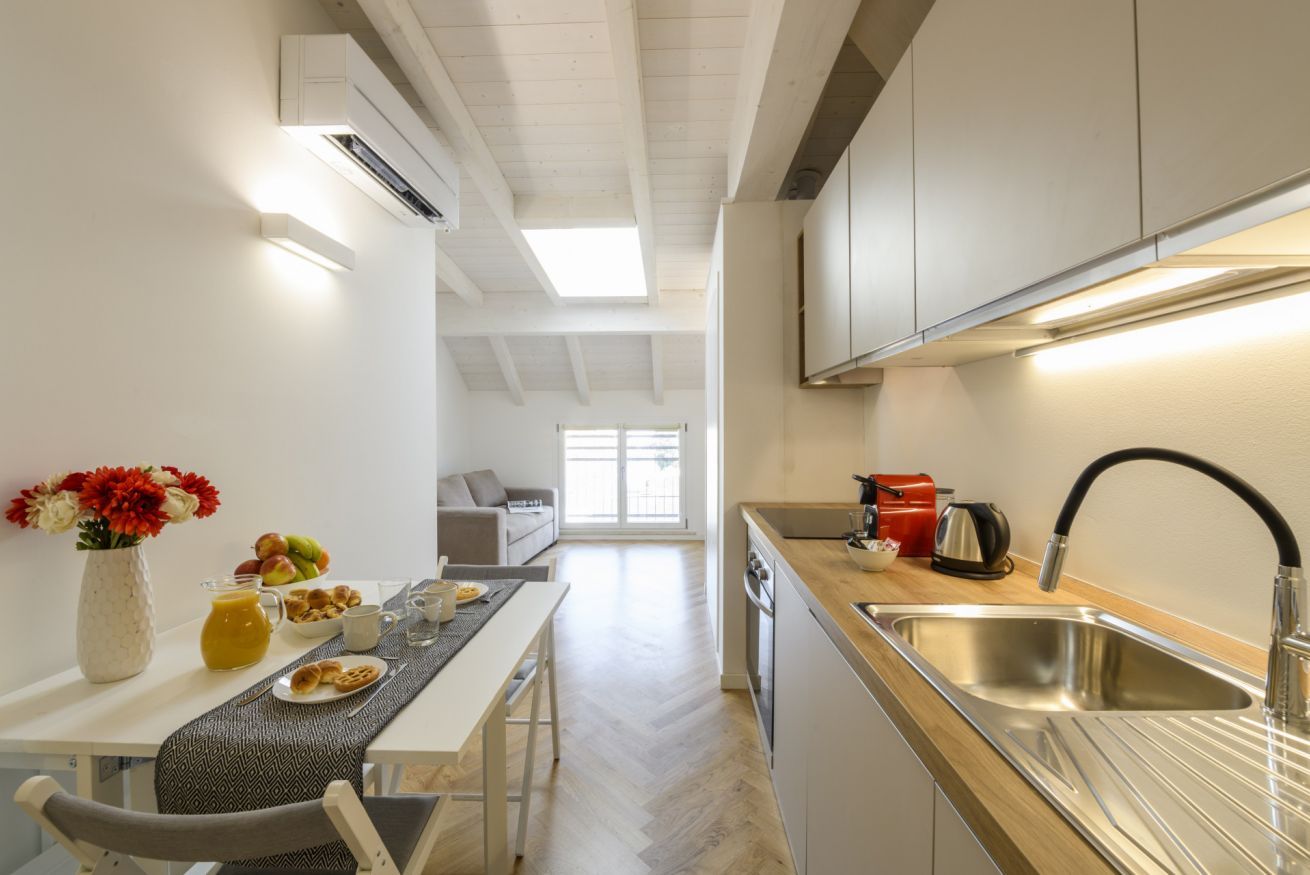 A modern kitchen with a dining area, a sink, and a window providing natural light.