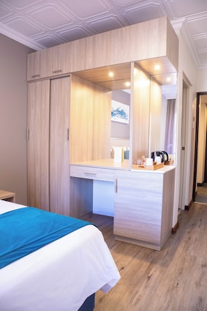 Una habitación de hotel con cama, escritorio con espejo y armario.
