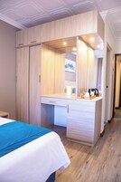 Una habitación de hotel con cama, escritorio con espejo y armario.