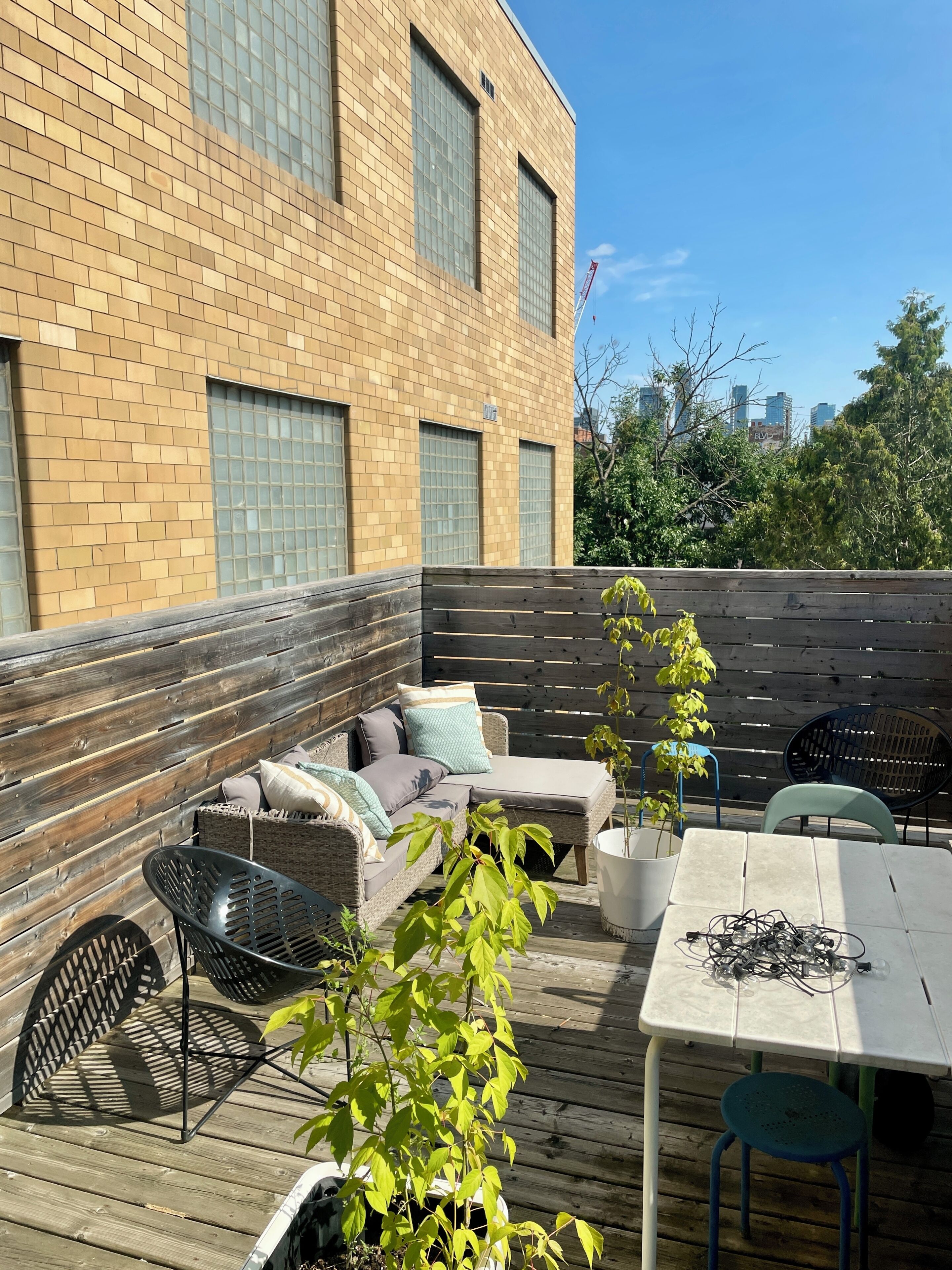 A wooden deck with a wicker sofa, a table, and chairs.