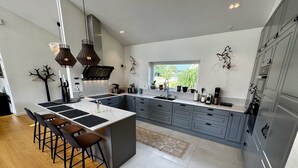 Cozinha moderna com ilha central, banquetas e uma grande janela que oferece luz natural.