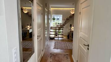 A hallway with a staircase leading to a second floor, a large mirror, and a rug.