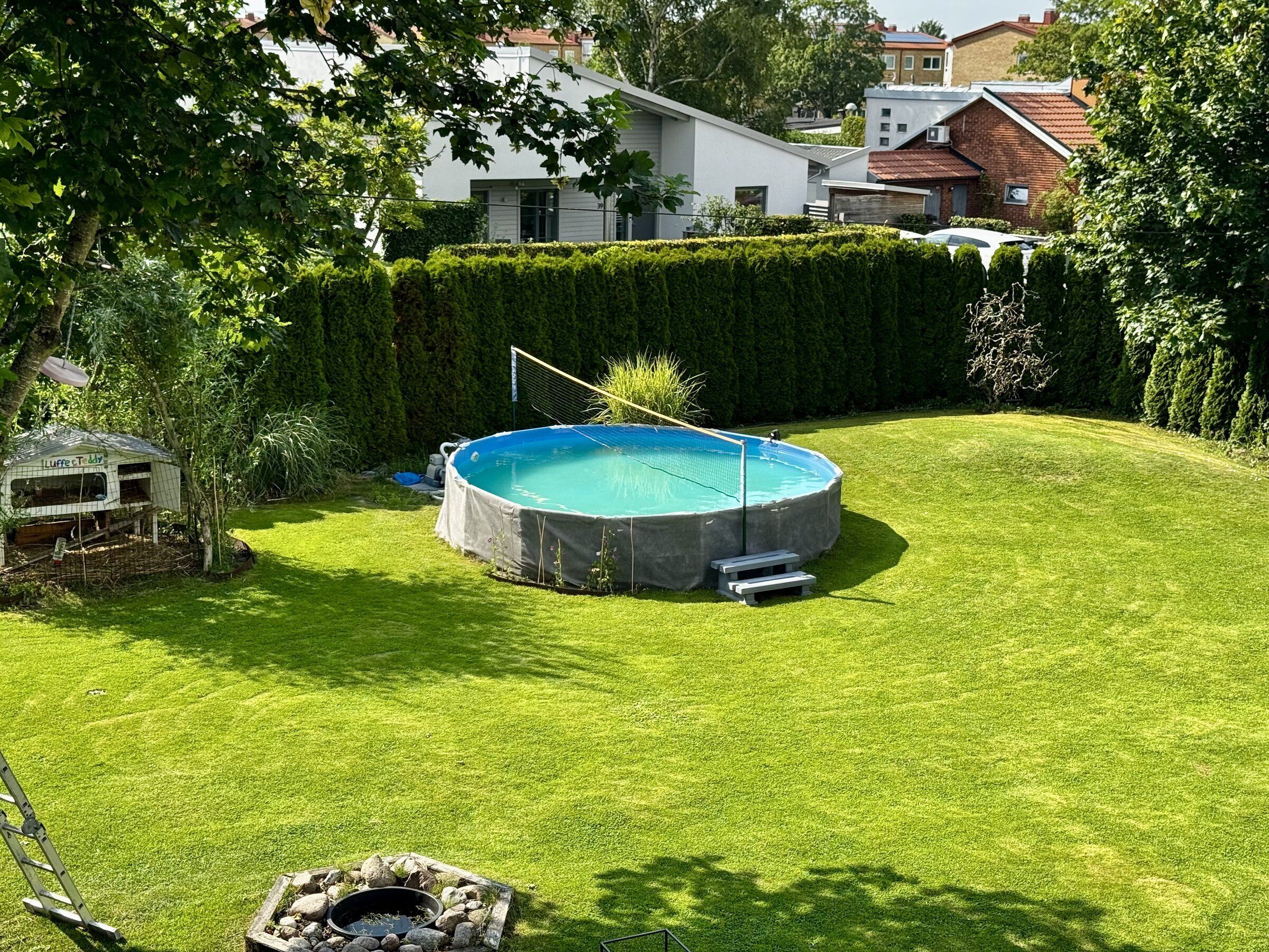 Un patio trasero con una piscina redonda, un jacuzzi pequeño y una casita de juegos de madera.