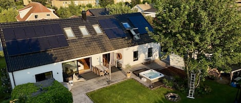 A house with a sloped roof, a hot tub, and a well-maintained lawn.