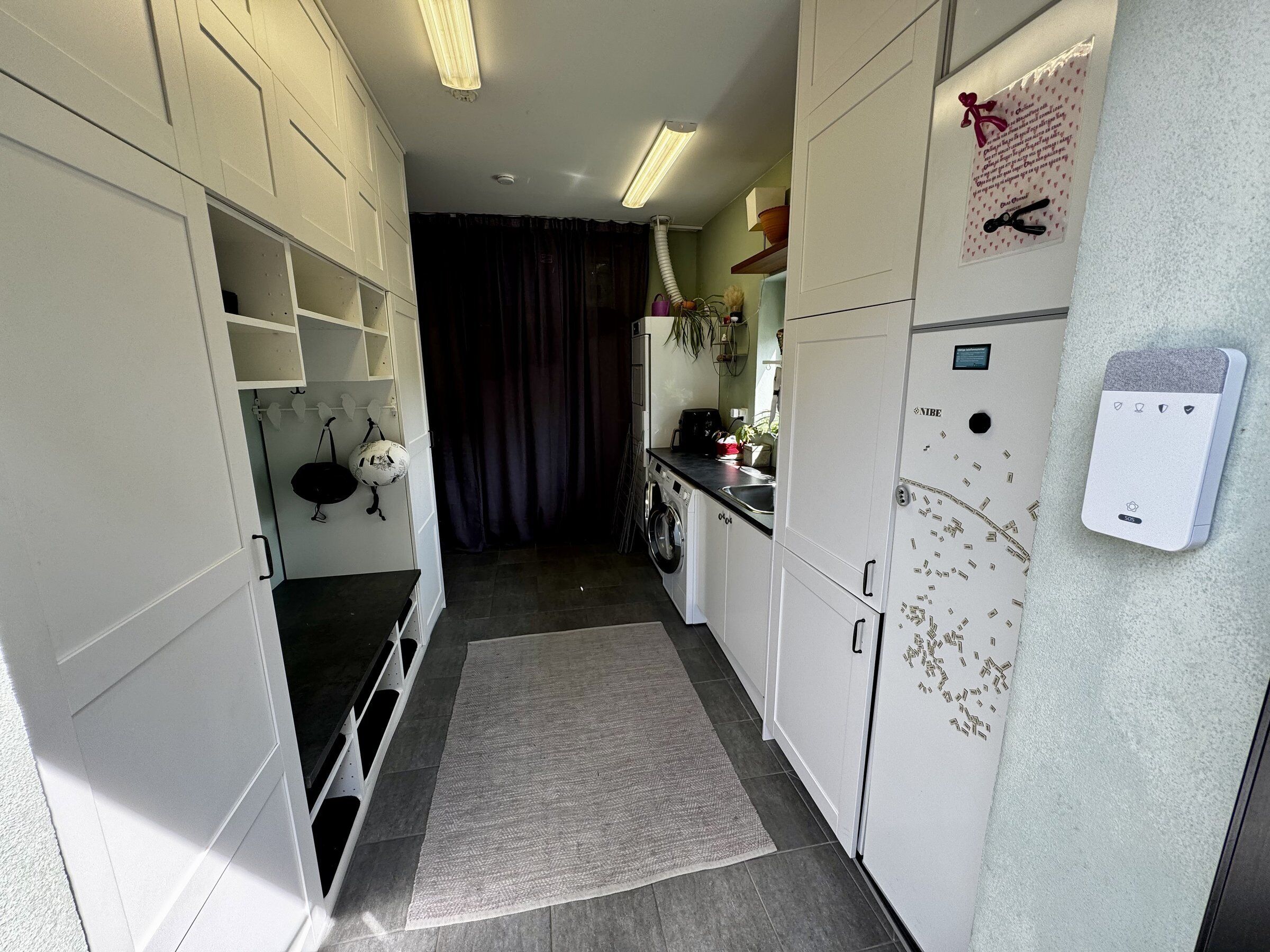 Una cocina compacta con armarios blancos, lavadora, refrigerador y una pequeña encimera.