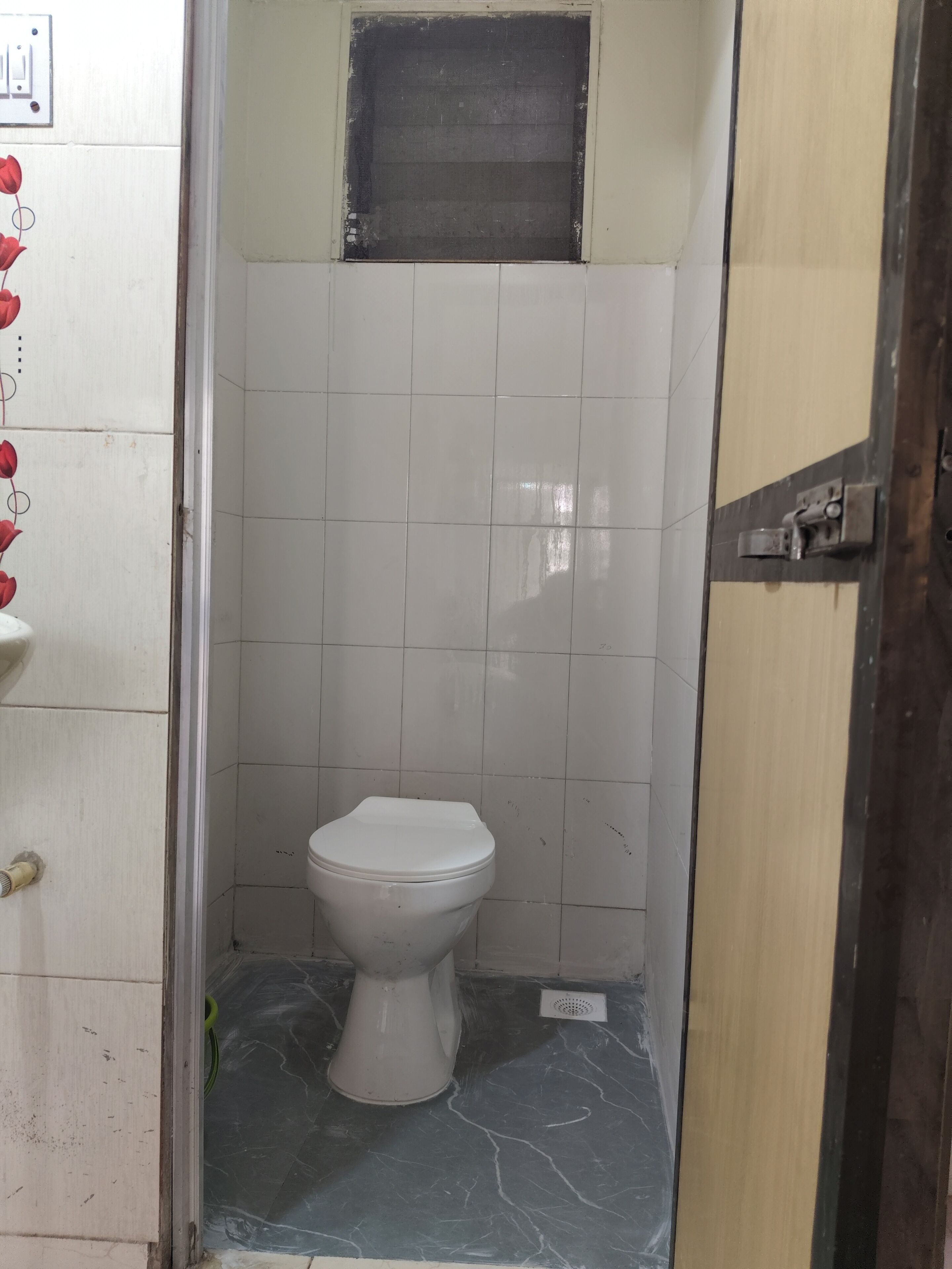 A bathroom with a white toilet, a shower area, and a tiled wall.