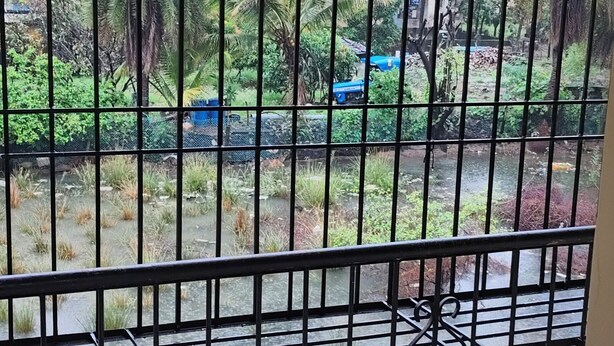 A view through a metal gate of a residential area with buildings and greenery.