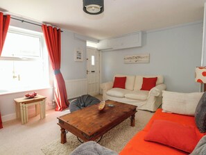 A living room with a sofa, a coffee table, and a window with curtains. - Driftmark (Weymouth)