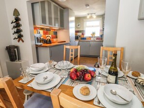 A dining area with a table set for four, including plates, glasses, and a bottle of wine. - Driftmark (Weymouth)