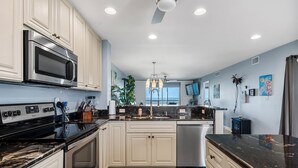 A modern kitchen with stainless steel appliances, white cabinetry, and a black countertop. - Between Blues | SK Collection by Siesta Stays (Sarasota)