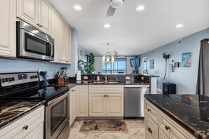A modern kitchen with stainless steel appliances, white cabinetry, and a black countertop. - Between Blues | SK Collection by Siesta Stays (Sarasota)