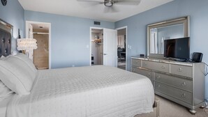 A bedroom with a bed, dresser, television, and a ceiling fan. - Between Blues | SK Collection by Siesta Stays (Sarasota)