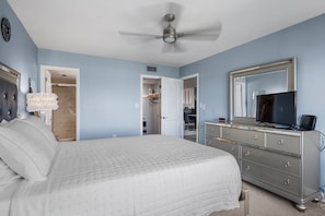 A bedroom with a bed, dresser, television, and a ceiling fan. - Between Blues | SK Collection by Siesta Stays (Sarasota)