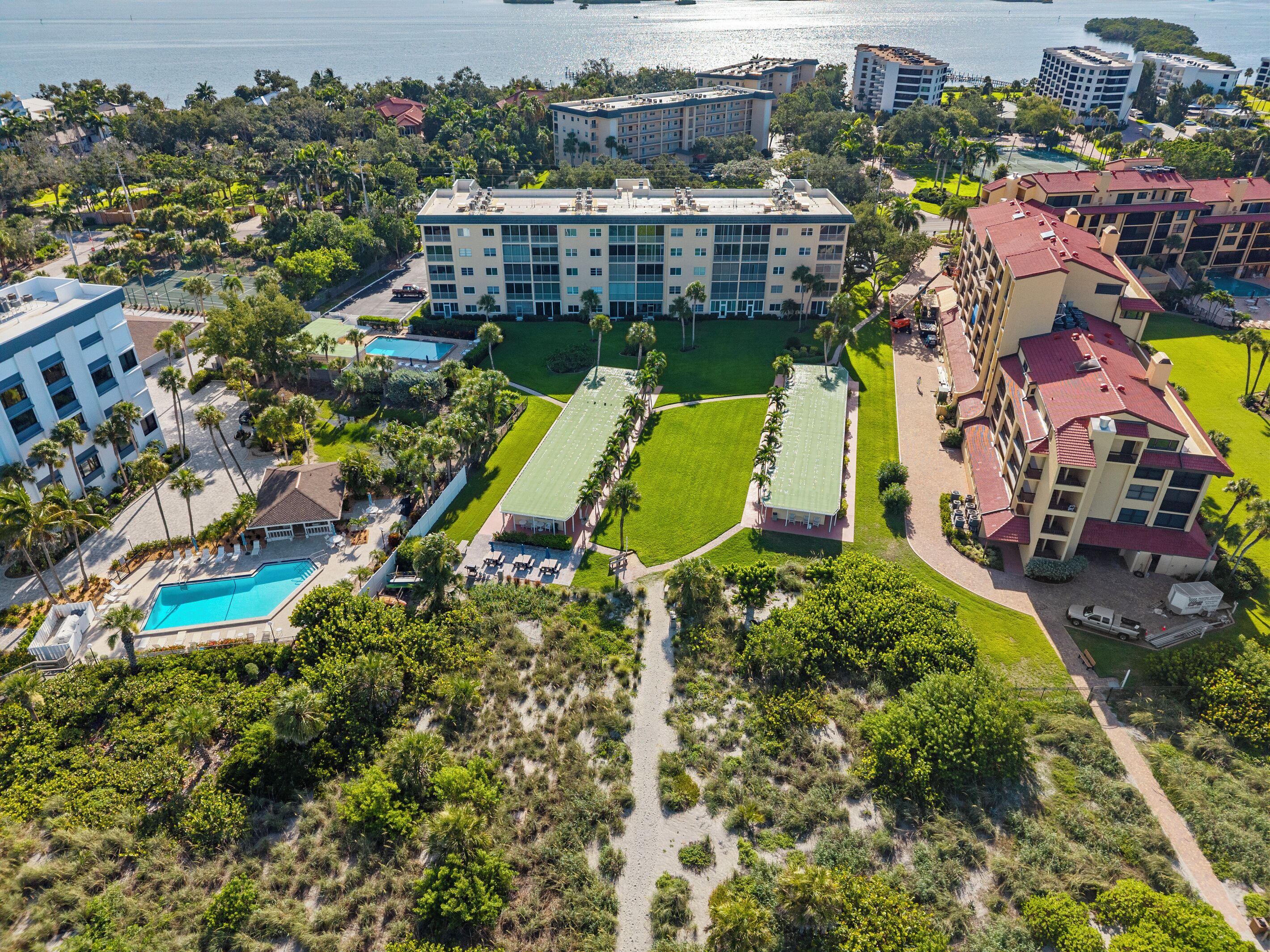 A multi-story hotel with a swimming pool, tennis courts, and a landscaped courtyard.
