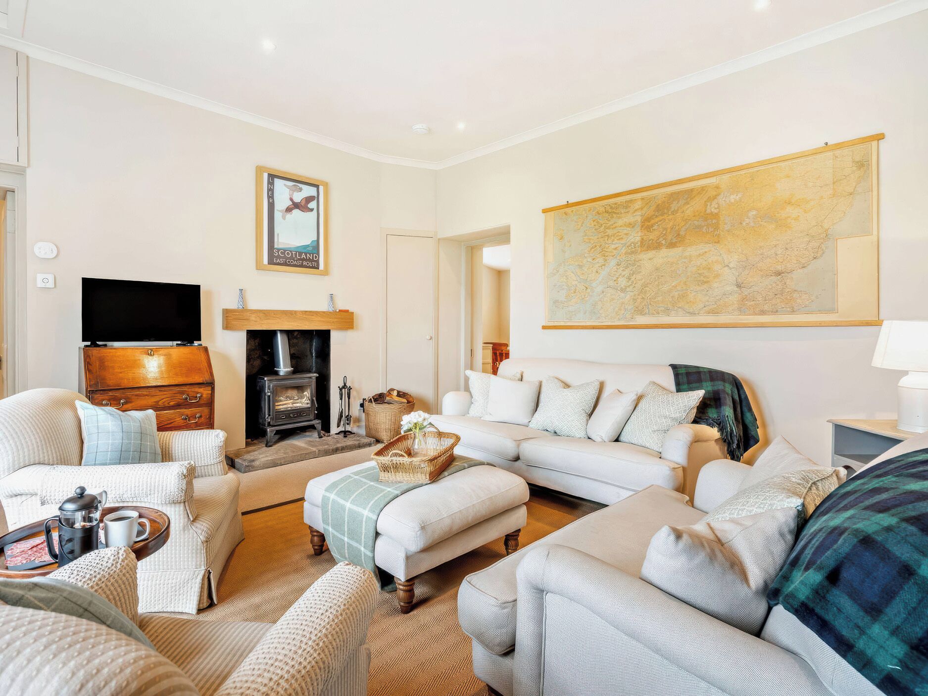 A cozy living room with a fireplace, comfortable seating, a television, and a map on the wall.