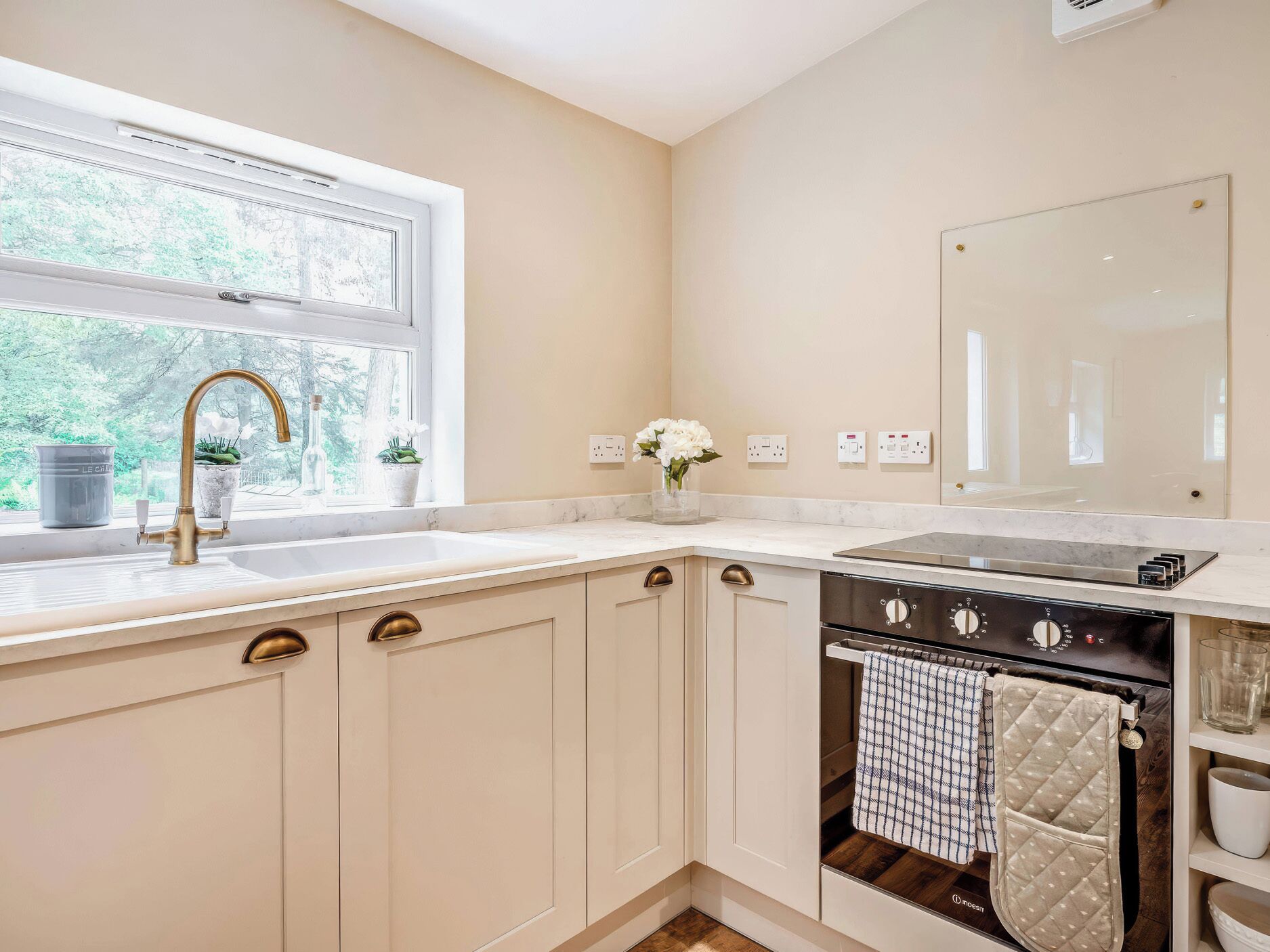A kitchen with a window, a sink, a stove, and cabinets.