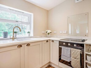 A kitchen with a window, a sink, a stove, and cabinets. - Upper Hillside Cottage (Blairgowrie)