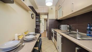 Cocina compacta con comedor, equipada con electrodomésticos modernos y una mesa para dos.