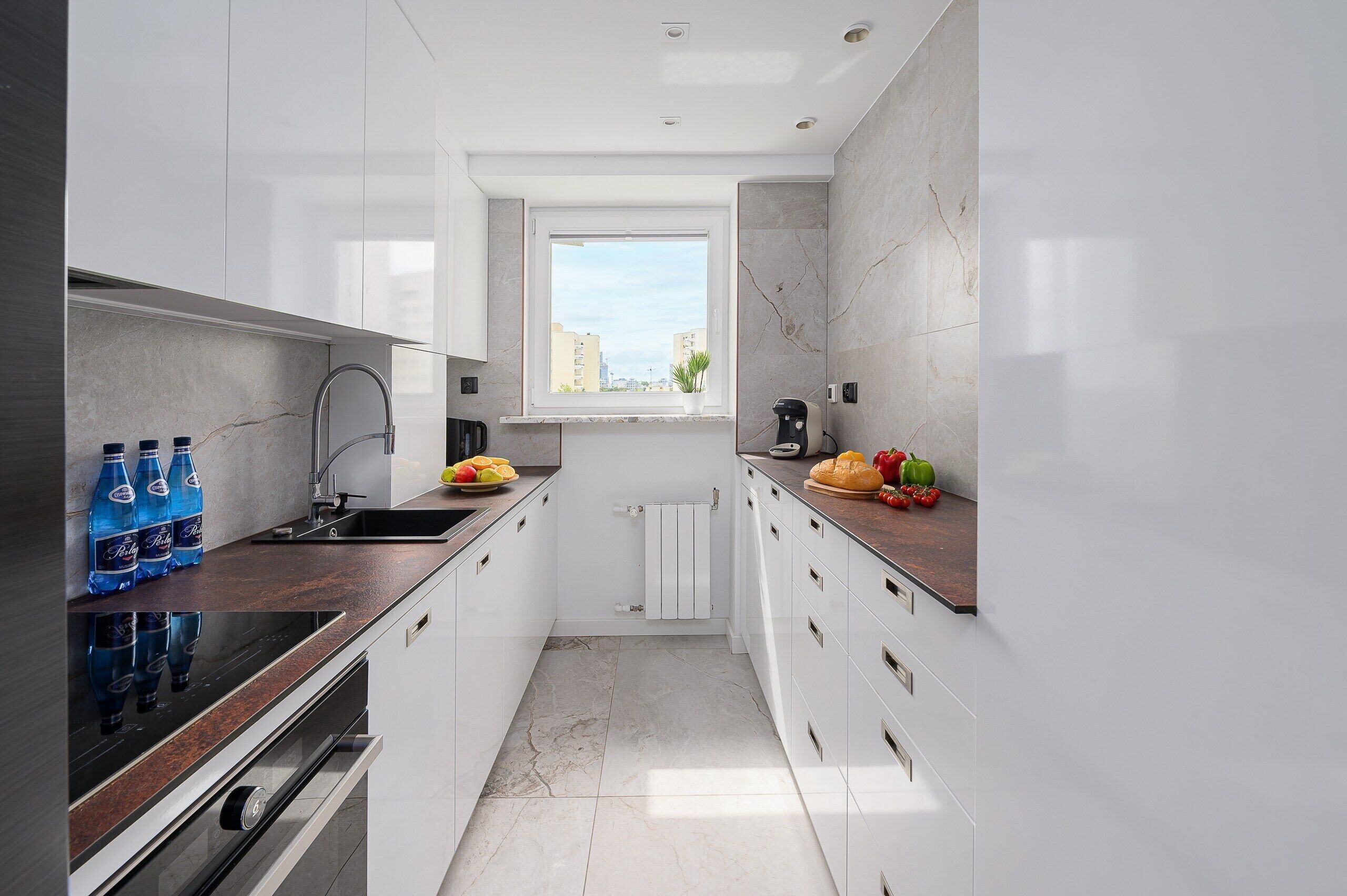 Una cocina moderna con armarios blancos, horno integrado y ventana que proporciona luz natural.