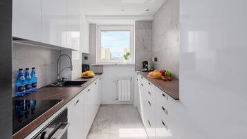 Una cocina moderna con armarios blancos, horno integrado y ventana que proporciona luz natural.