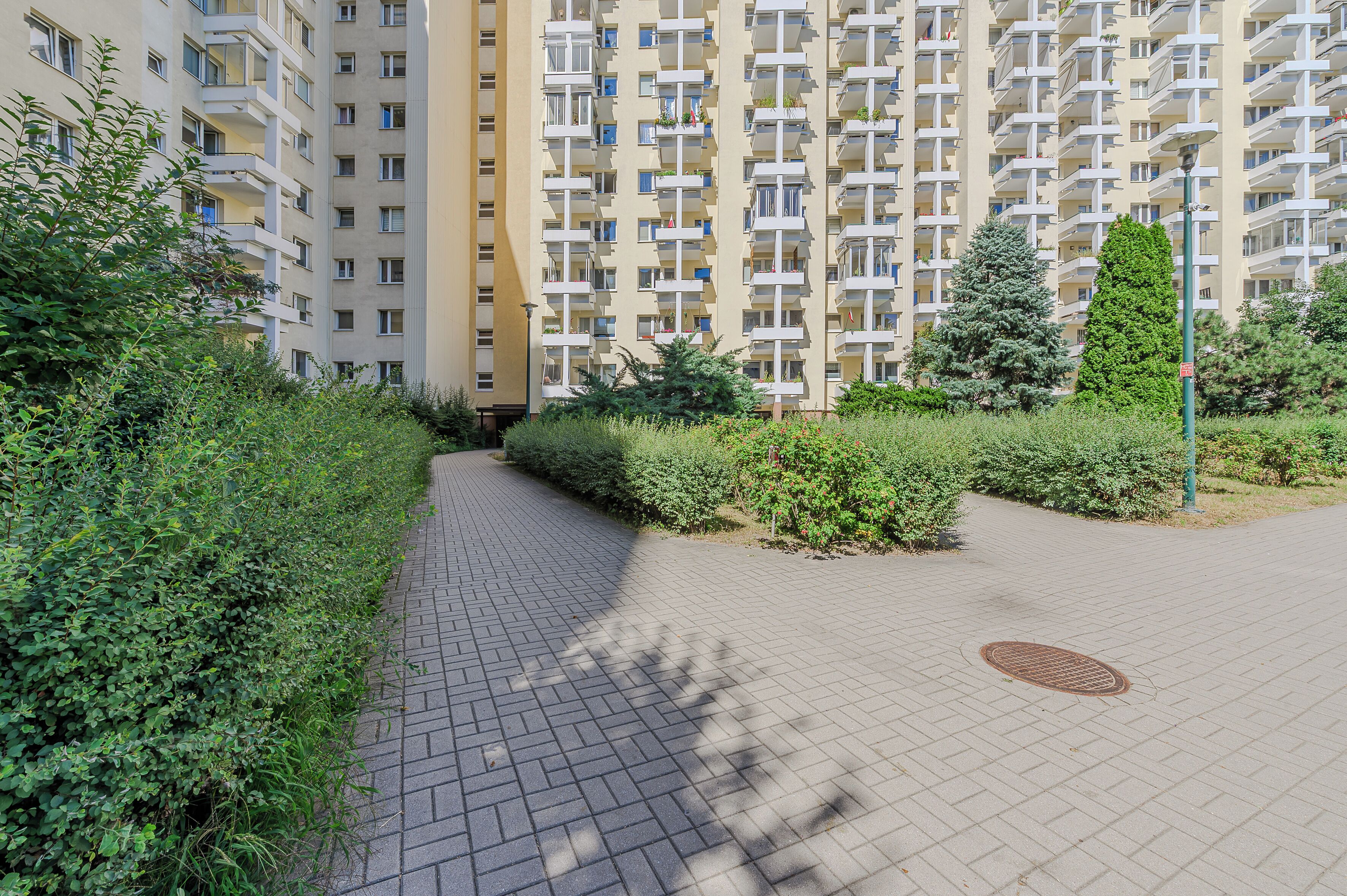 Un edificio residencial de varios pisos con un sendero pavimentado que lleva a la entrada.