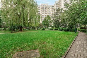 A park with a grassy area, trees, and a pathway. - Lumina 3-room Apart near Arkadia Mall  (Warszawa)