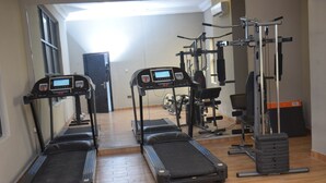 Ein Fitnessstudio mit Laufbändern, Krafttrainingsgeräten und einer Spiegelwand.